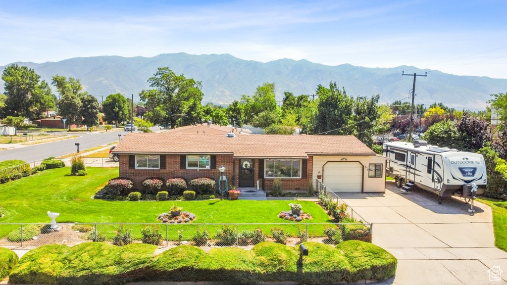View of front facade featuring a garage, concrete driveway, a mountain view, and brick siding