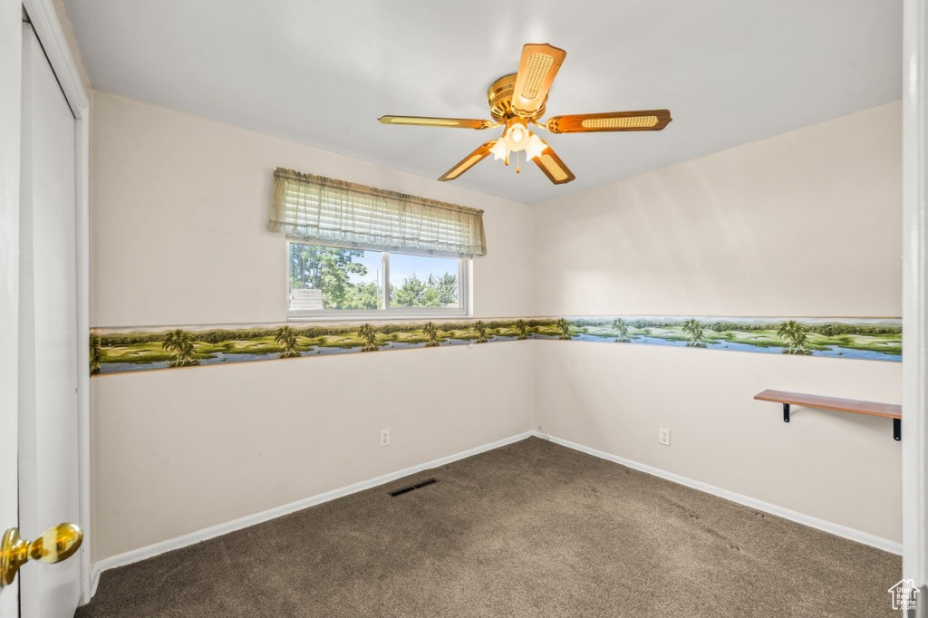 Carpeted empty room featuring a ceiling fan and baseboards