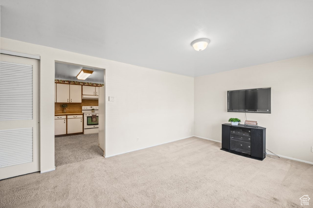 Unfurnished living room featuring light colored carpet and baseboards