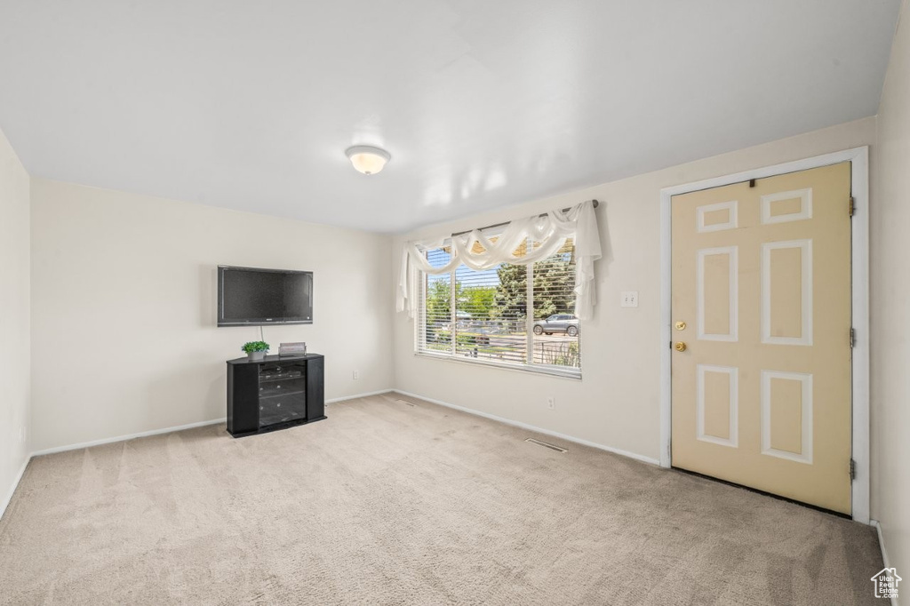 Unfurnished living room with carpet flooring and baseboards