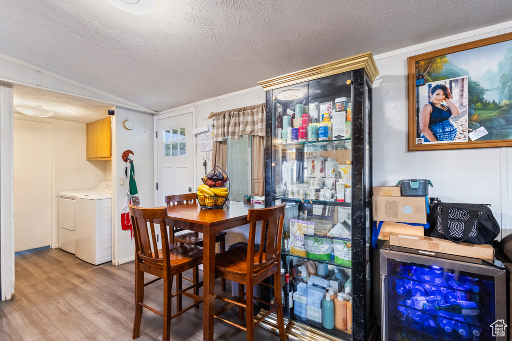 Dining area featuring separate washer and dryer, wood finished floors, beverage cooler, and a textured ceiling