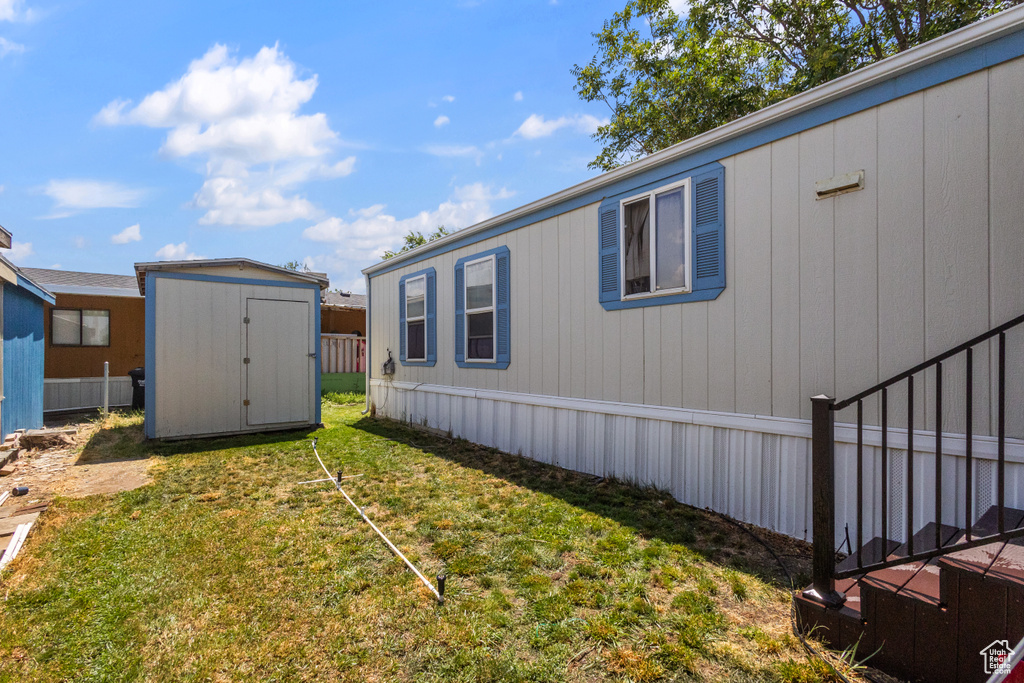 View of side of home featuring a storage shed and a yard