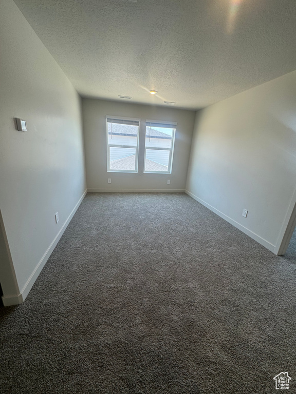 Unfurnished room featuring a textured ceiling and carpet