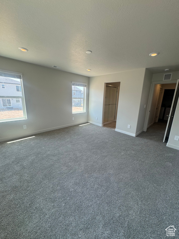 Carpeted empty room with a textured ceiling and recessed lighting