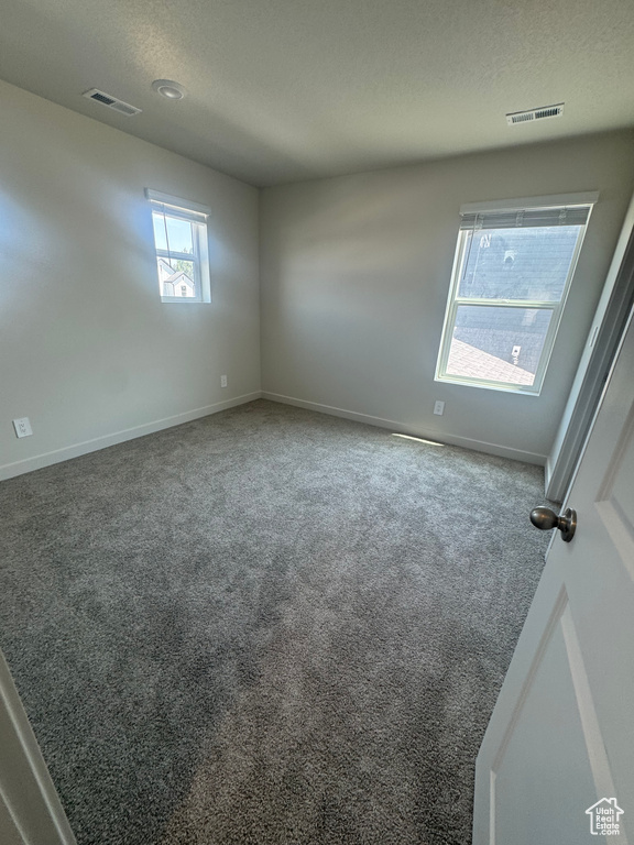 Empty room with carpet and a textured ceiling