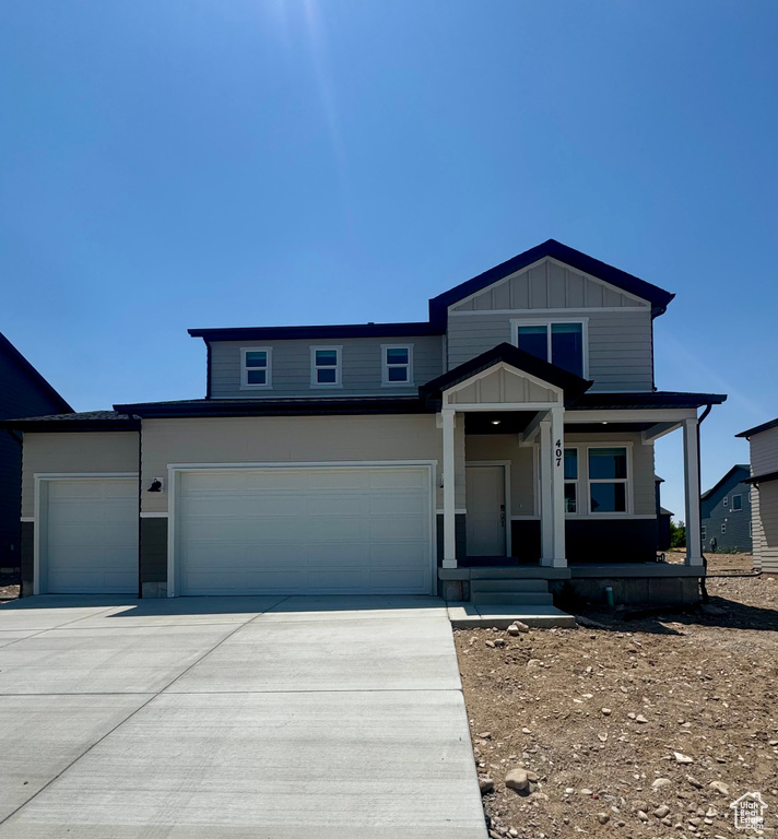 View of front of home with driveway, a porch, an attached garage, and board and batten siding