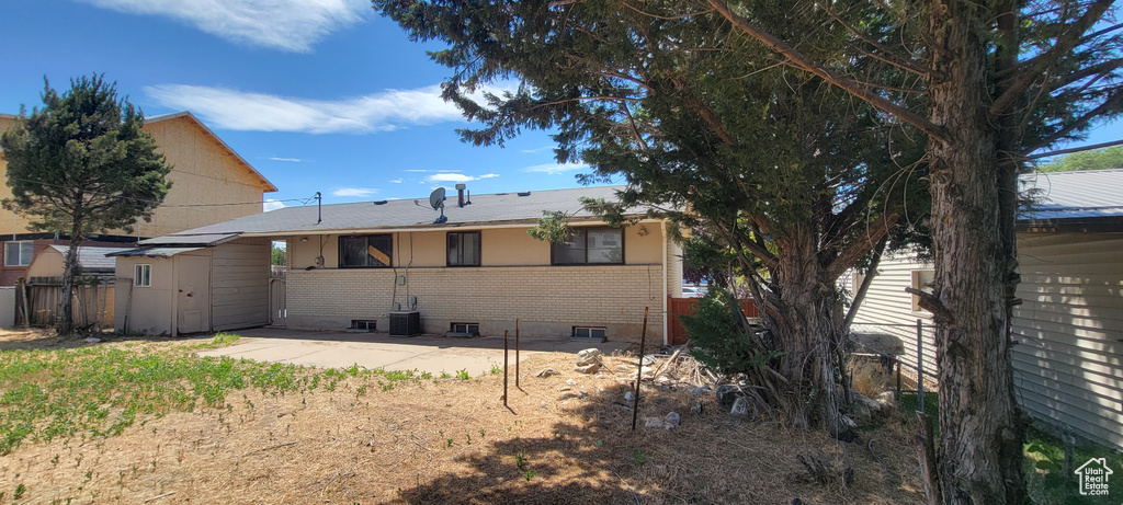 Rear view of house with brick siding, a storage shed, and a patio area