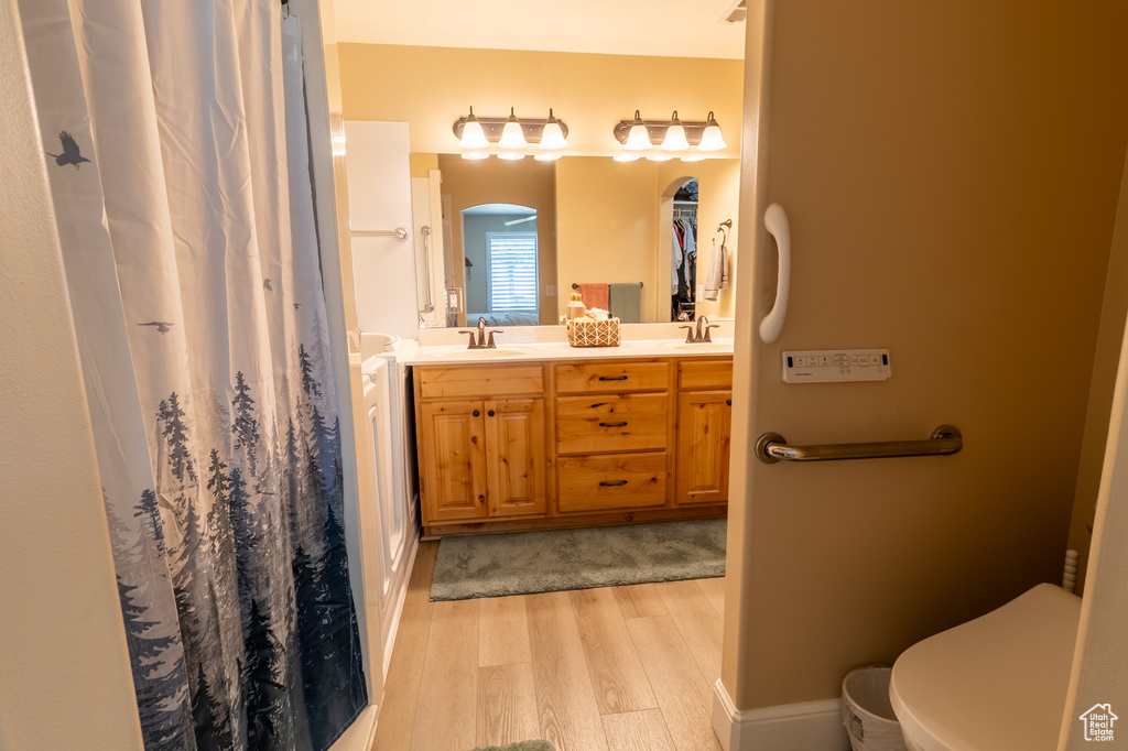 Full bathroom featuring wood finished floors, double vanity, and a shower with curtain