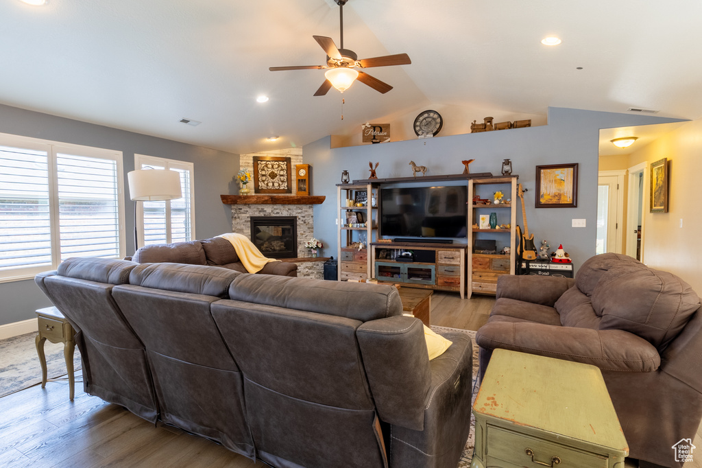 Living room with a ceiling fan, light wood-type flooring, vaulted ceiling, a fireplace, and recessed lighting
