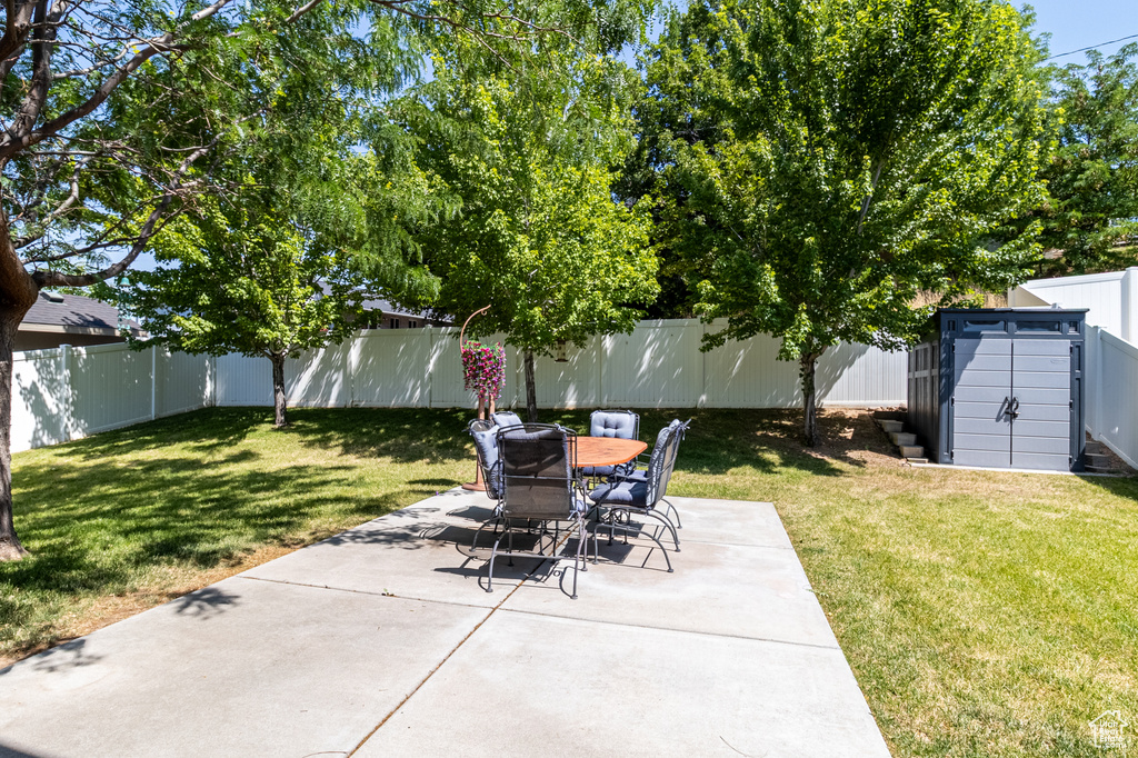 Fenced backyard featuring a patio, a storage unit, and outdoor dining area