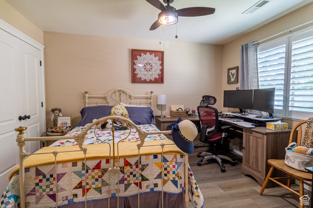 Bedroom featuring light wood-style floors, an office area, and a ceiling fan