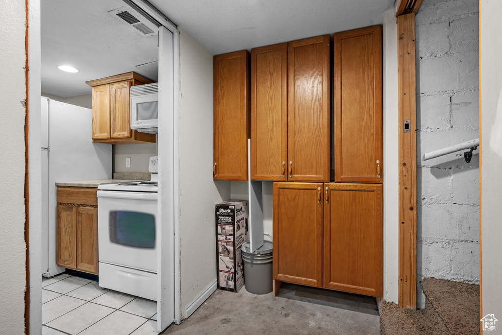 Kitchen with white appliances, concrete floors, brown cabinetry, light countertops, and recessed lighting