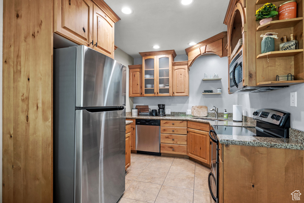 Kitchen with appliances with stainless steel finishes, open shelves, dark stone countertops, light tile patterned floors, and recessed lighting