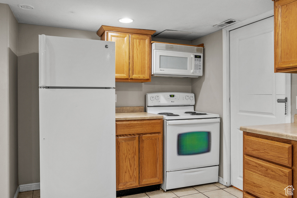 Kitchen featuring white appliances, light tile patterned floors, recessed lighting, light countertops, and brown cabinets