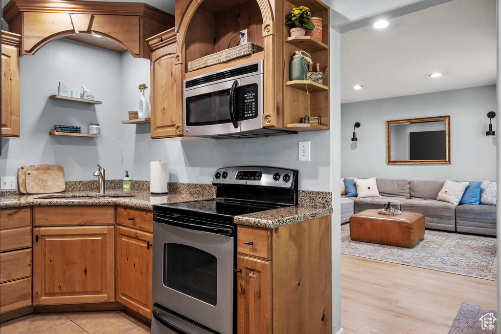 Kitchen featuring open shelves, stainless steel appliances, open floor plan, recessed lighting, and light wood finished floors