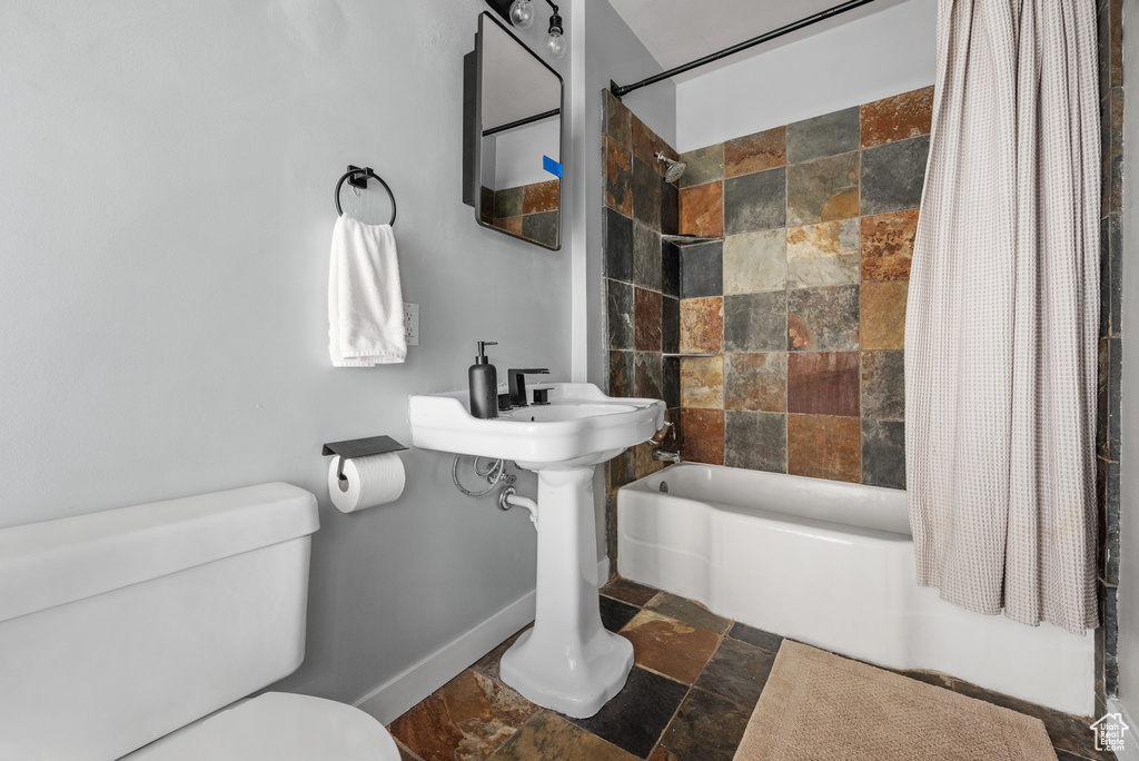 Full bathroom with stone tile floors and shower / bathtub combination with curtain