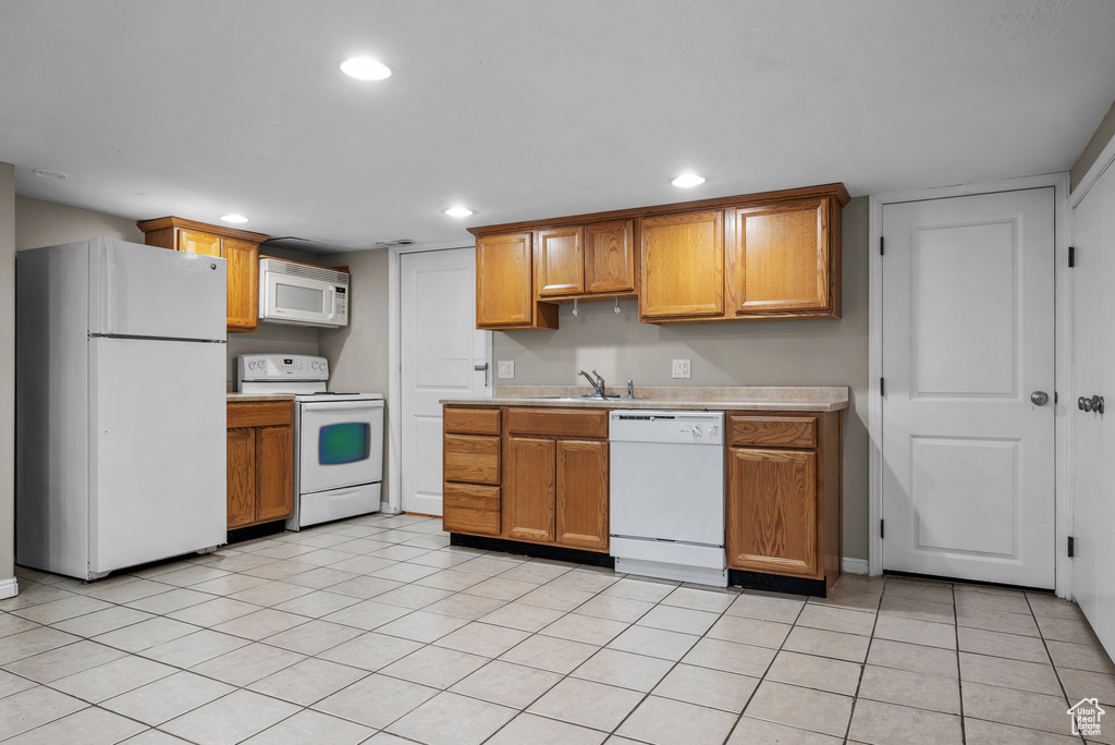 Kitchen featuring white appliances, light countertops, recessed lighting, brown cabinetry, and light tile patterned flooring