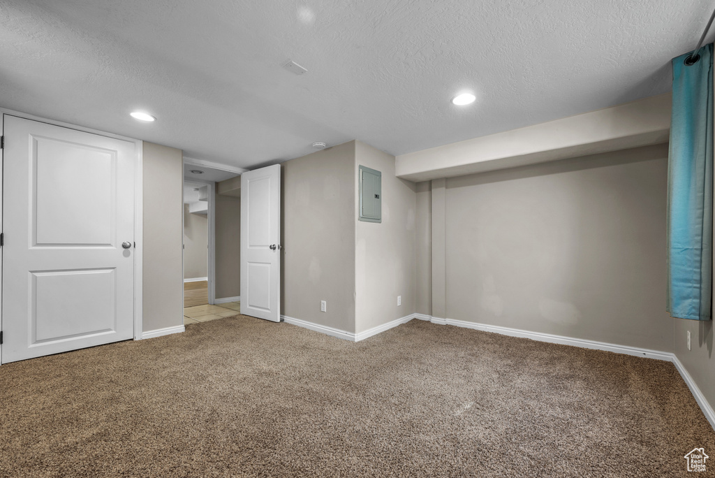 Finished basement featuring carpet flooring, electric panel, a textured ceiling, and recessed lighting