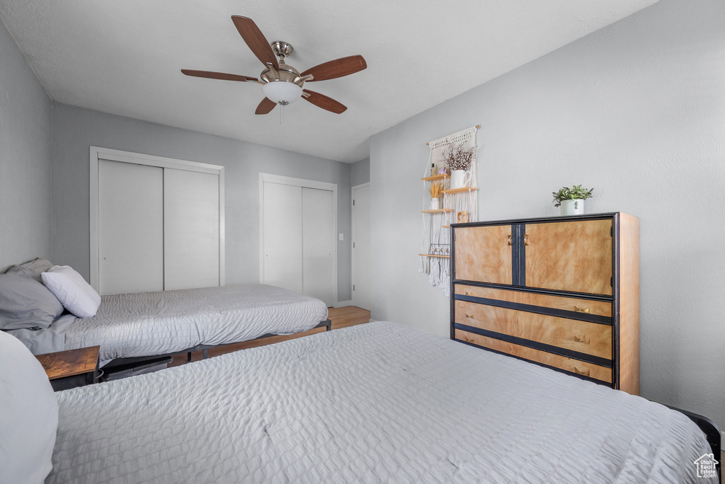 Bedroom with two closets, ceiling fan, and wood finished floors