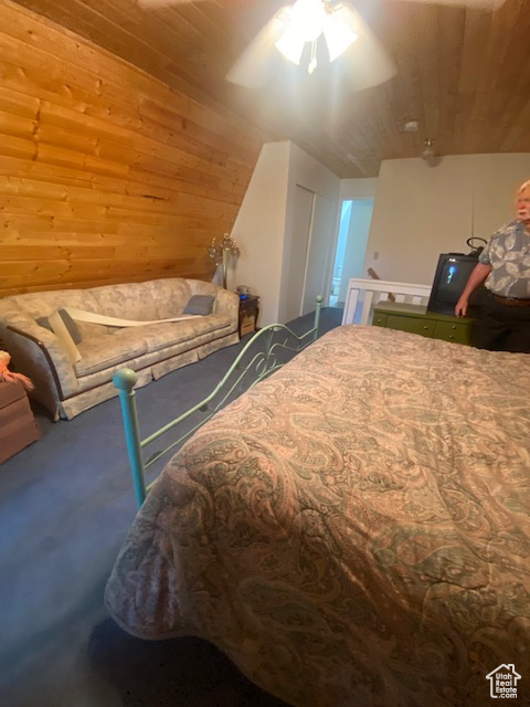Carpeted bedroom with wooden walls and wooden ceiling