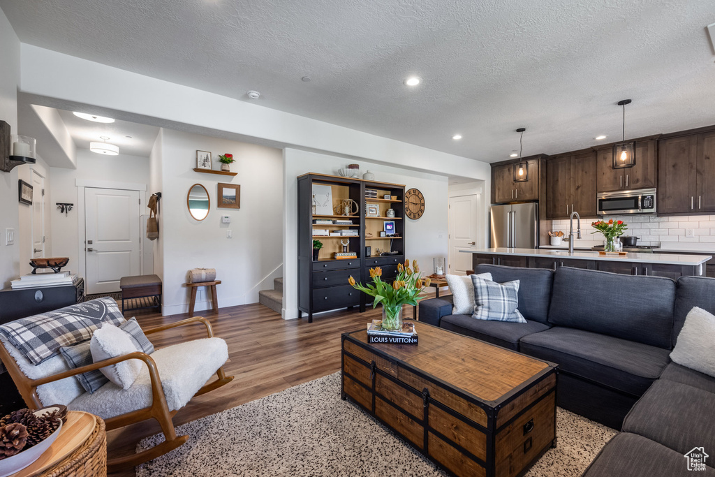 Living area featuring stairway, light wood-style flooring, a textured ceiling, and recessed lighting