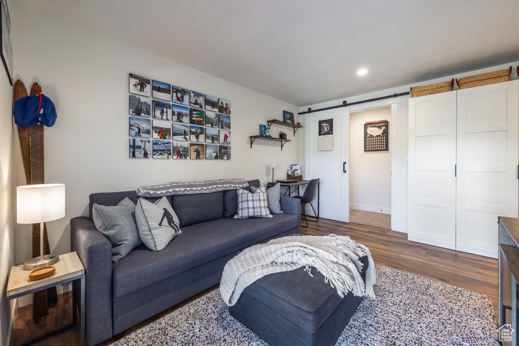 Living room with wood finished floors, a barn door, and recessed lighting