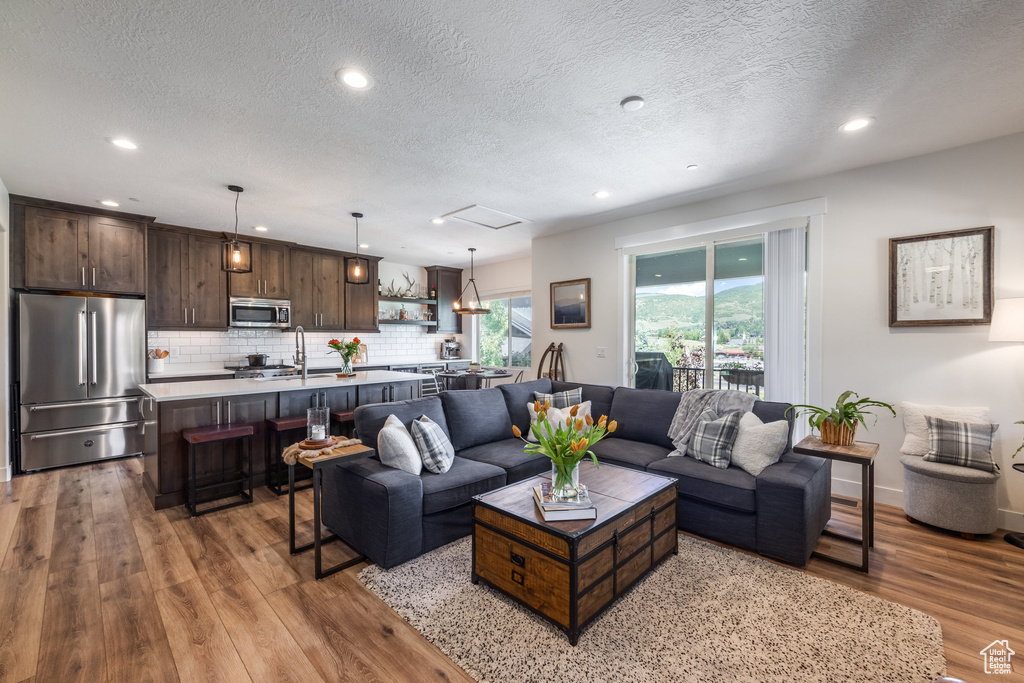 Living room featuring wood finished floors, a textured ceiling, and recessed lighting