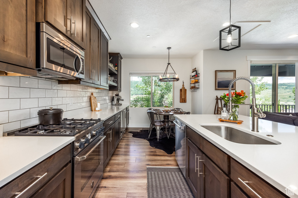 Kitchen featuring stainless steel appliances, light countertops, light wood finished floors, tasteful backsplash, and a textured ceiling