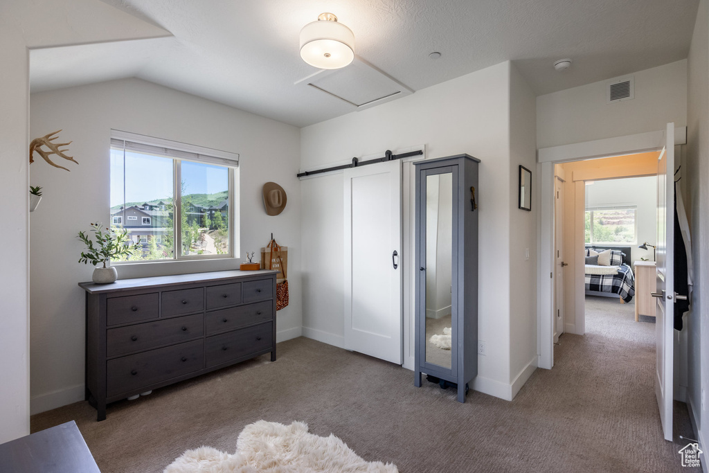 Bedroom featuring carpet floors, vaulted ceiling, a barn door, and attic access