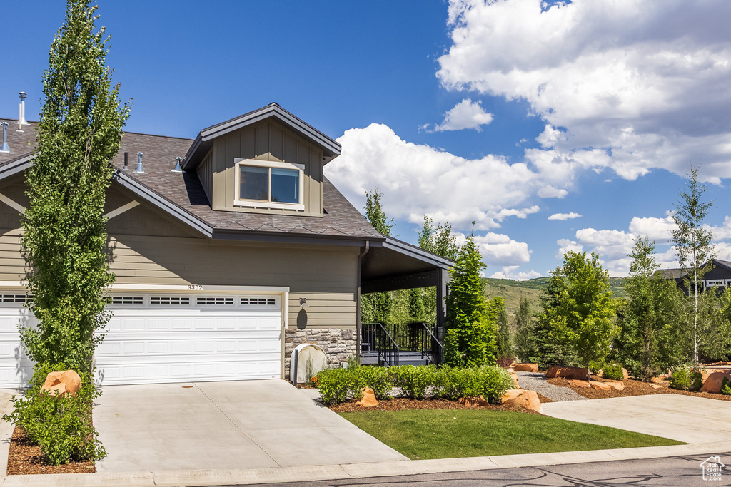 View of front of property featuring concrete driveway, a garage, stone siding, and a porch