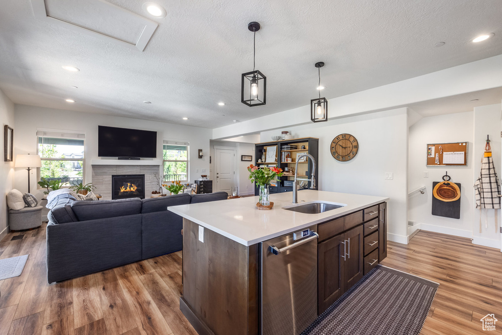 Kitchen with dishwasher, light countertops, light wood-style floors, open floor plan, and a textured ceiling