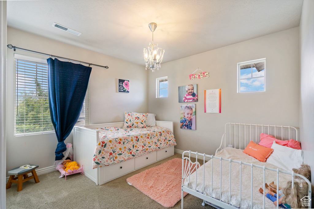 Carpeted bedroom featuring a chandelier and baseboards