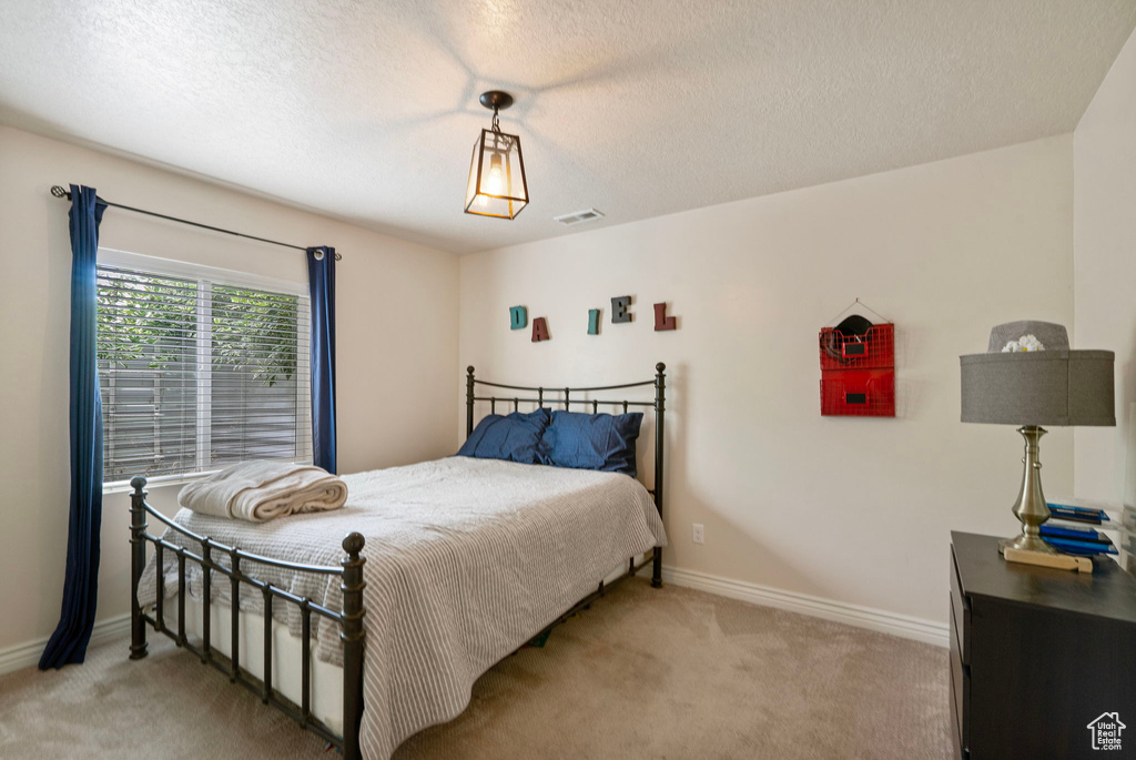 Bedroom with light colored carpet and a textured ceiling