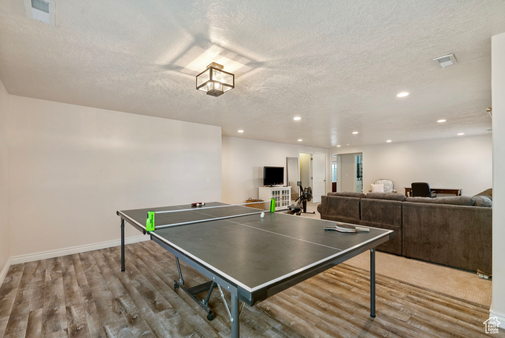 Recreation room featuring wood finished floors, a textured ceiling, and recessed lighting