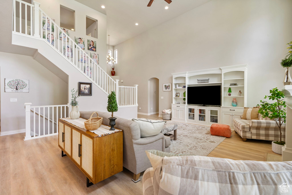 Living area featuring a high ceiling, light wood-type flooring, arched walkways, ceiling fan, and recessed lighting