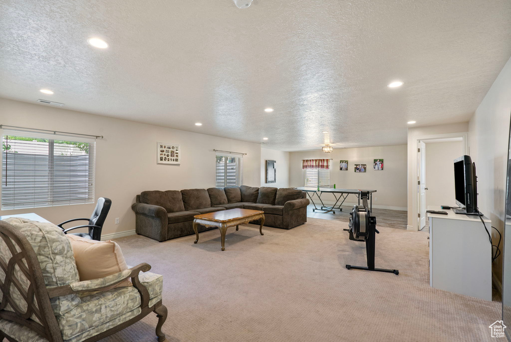 Living room with recessed lighting, light carpet, healthy amount of natural light, and a textured ceiling