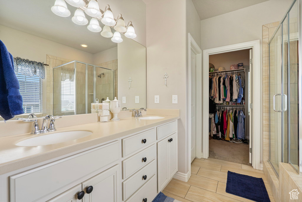 Full bath with a stall shower, a spacious closet, double vanity, and tile patterned flooring