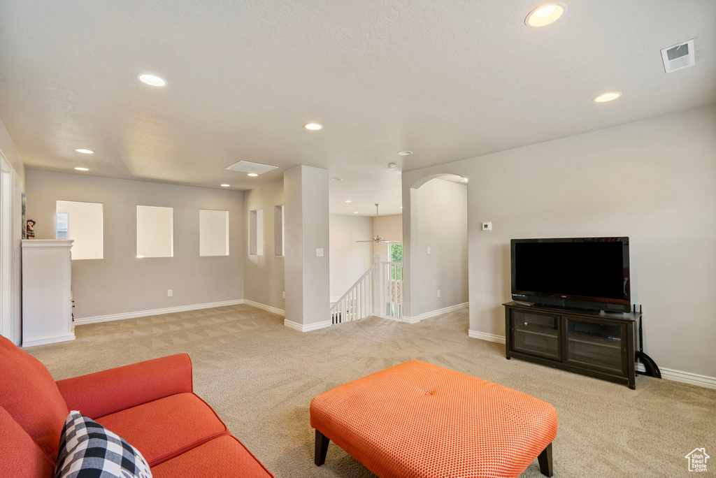 Living room with light carpet, recessed lighting, and arched walkways
