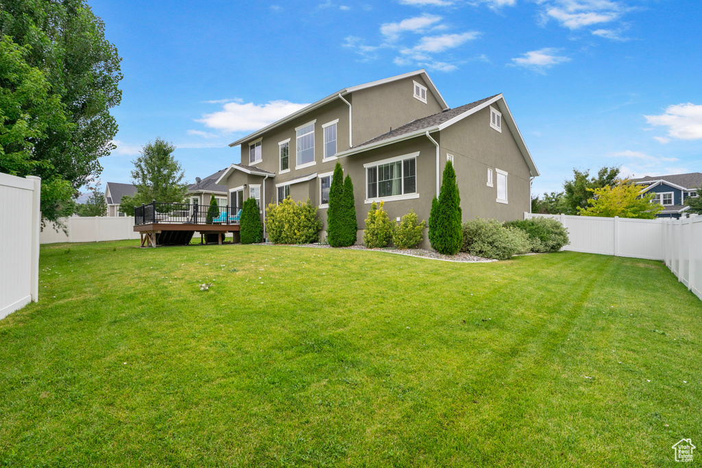 Rear view of property featuring a wooden deck, a fenced backyard, and stucco siding