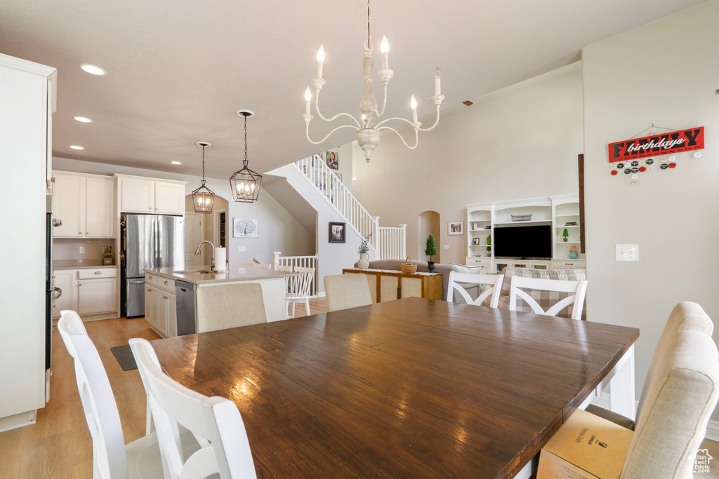 Dining area with recessed lighting, stairs, light wood-type flooring, arched walkways, and a chandelier