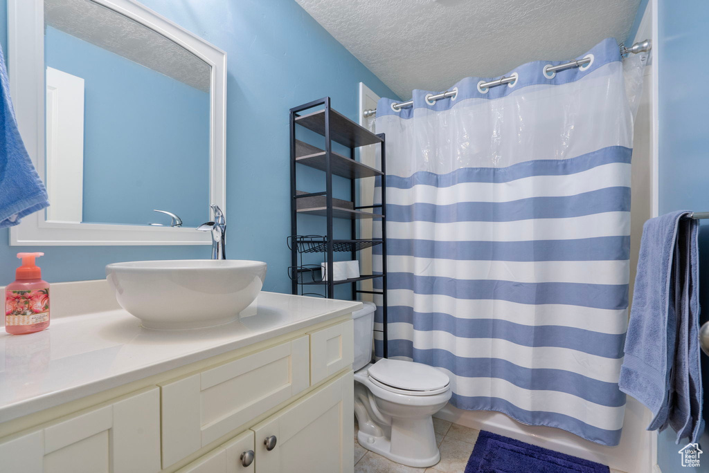 Bathroom featuring a textured ceiling, vanity, tile patterned flooring, and curtained shower