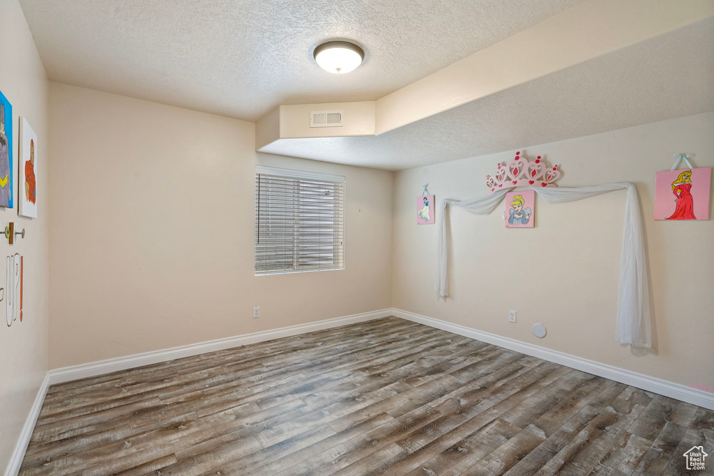 Unfurnished room featuring a textured ceiling and wood finished floors