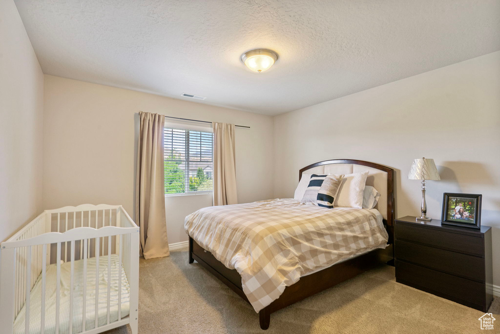 Bedroom featuring light carpet and a textured ceiling