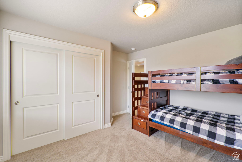 Bedroom with light carpet and a closet