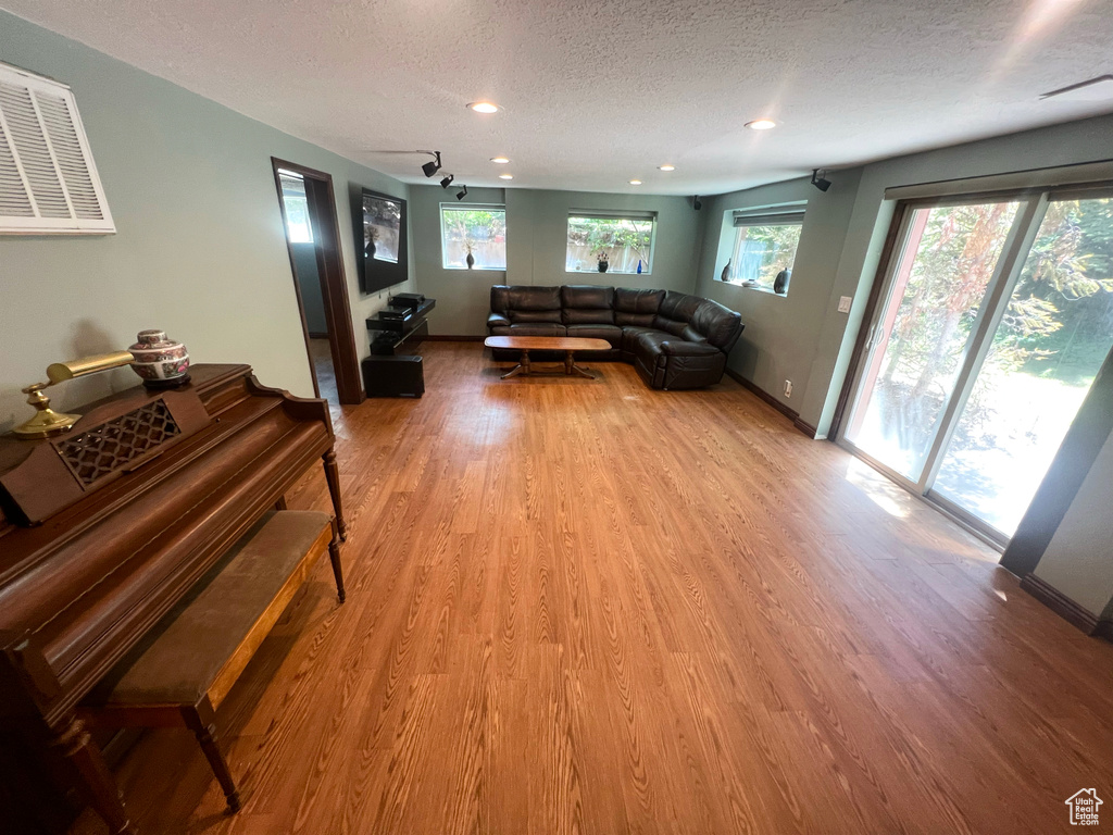 Living room with a textured ceiling, light wood-type flooring, and recessed lighting