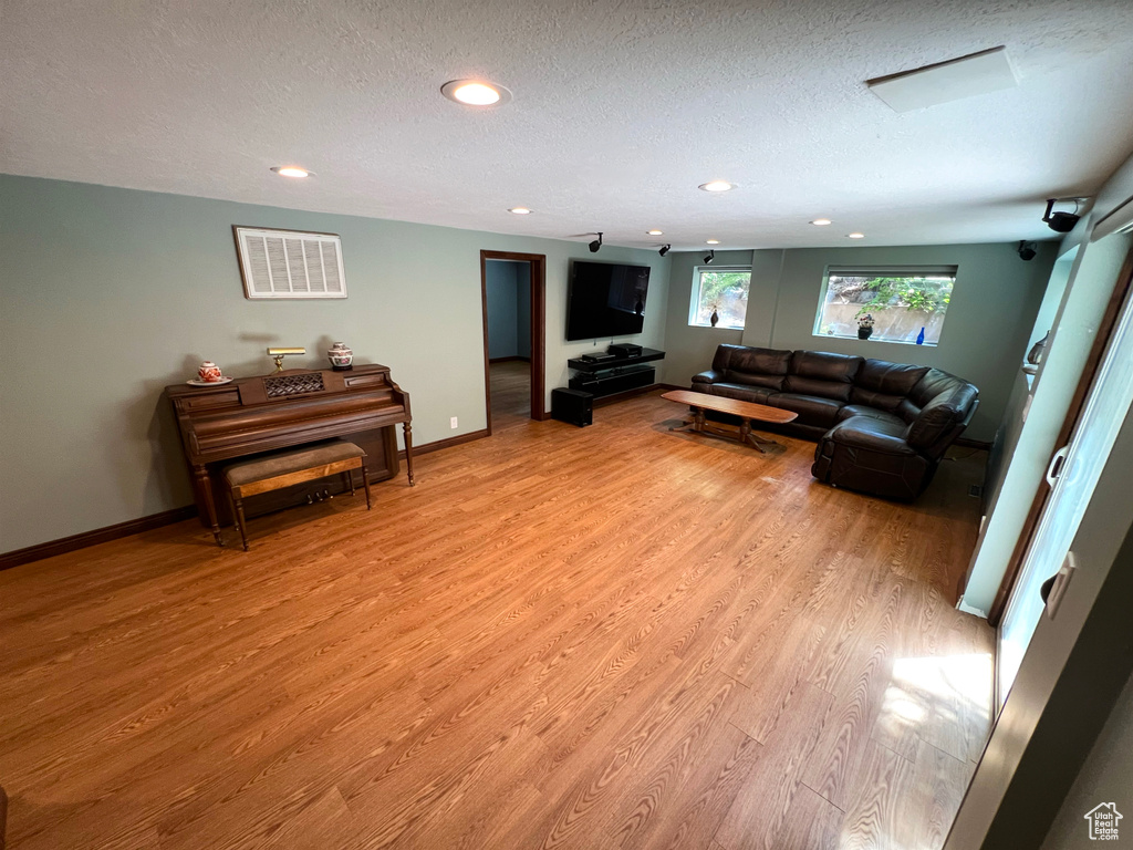 Living area with light wood-style flooring, recessed lighting, and a textured ceiling