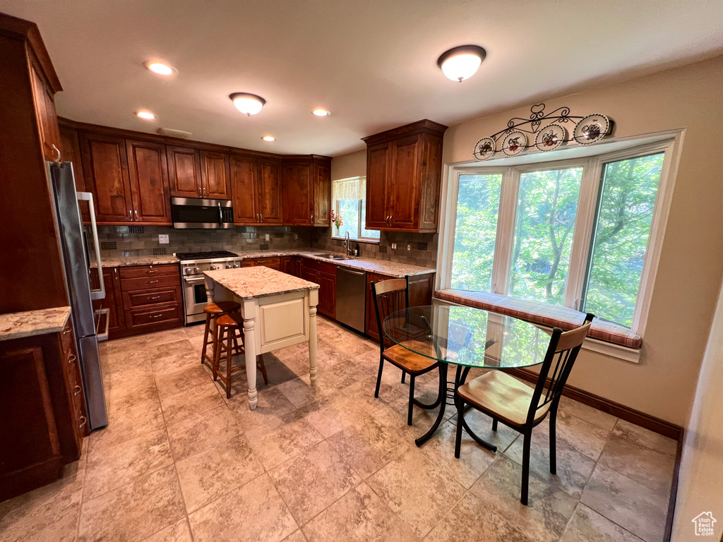 Kitchen featuring stainless steel appliances, decorative backsplash, light stone countertops, and recessed lighting
