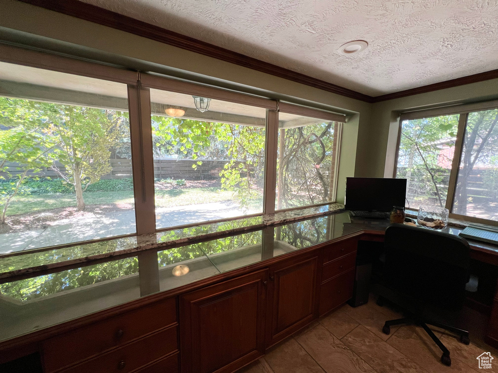 Office with a textured ceiling, healthy amount of natural light, light tile patterned floors, and ornamental molding