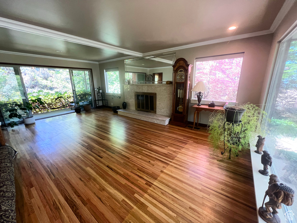 Unfurnished living room with wood finished floors, a fireplace, and ornamental molding