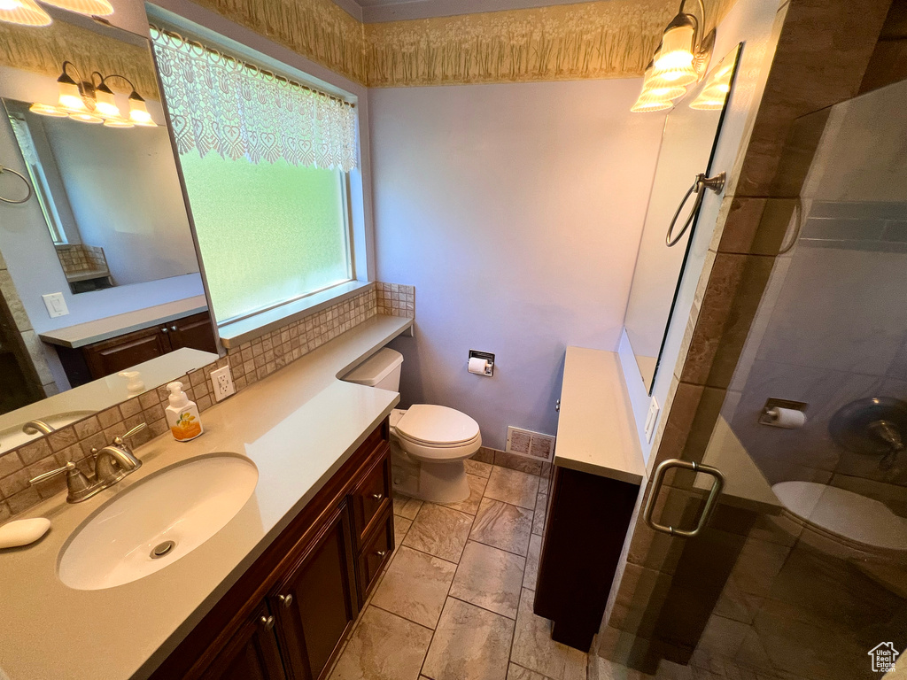 Bathroom featuring vanity, a stall shower, and decorative backsplash